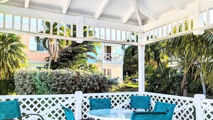 A covered outdoor seating area with white lattice railings and blue cushioned chairs.