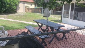 Ein eingezäunter Garten mit Picknicktischen und Grill.