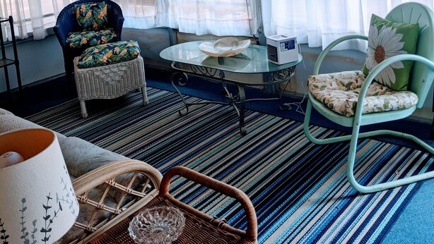 Ein Zimmer mit einem Korbstuhl, einem Tisch mit einer Schale und einem Korb mit einer Lampe.