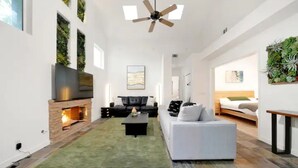 Un salon moderne avec une cheminée, un canapé, une table basse et un téléviseur.