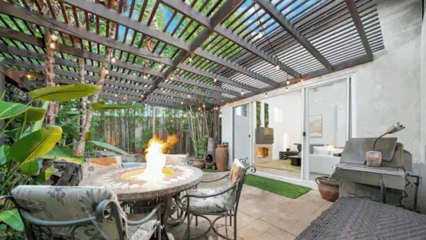 Une terrasse extérieure avec une table ronde, des chaises et un foyer.