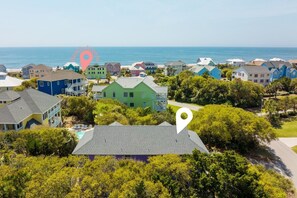 A coastal residential area with colorful houses, a beach in the background, and a clear sky. - 3BR Oceanview Duplex, beach and community pool access, in Spinnaker's Reach (Emerald Isle)