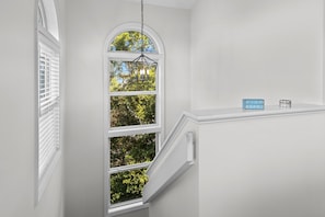 A staircase with white walls and a window with white blinds. - 3BR Oceanview Duplex, beach and community pool access, in Spinnaker's Reach (Emerald Isle)