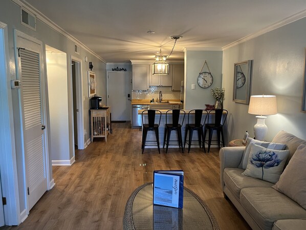 A modern living room with a sofa, a coffee table, and a kitchen in the background. - Peaceful 2BR Beach Condo with Pools, Tennis, Pickleball, Sauna, Gym & More! (Hilton Head Island)