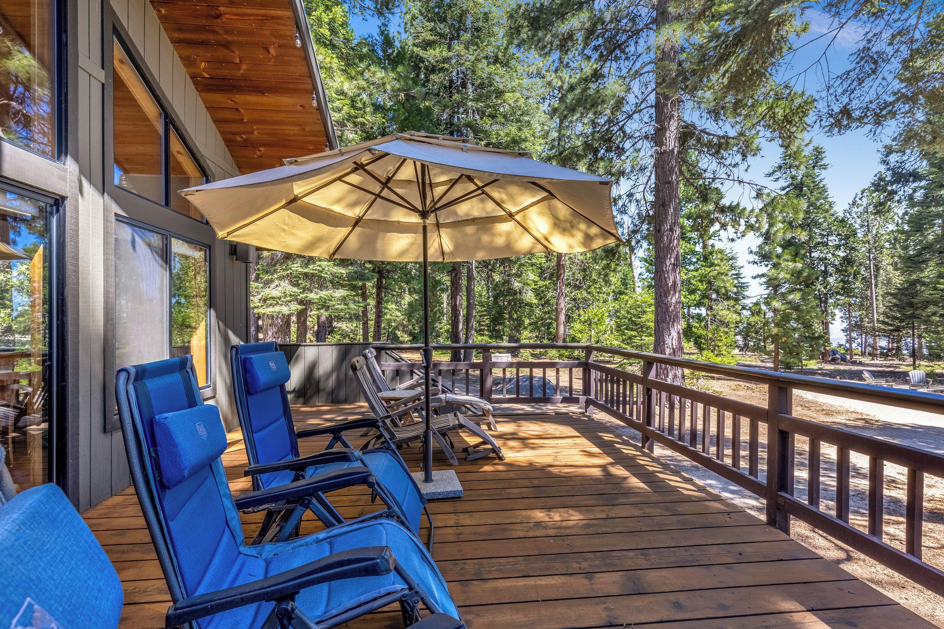Une terrasse en bois avec des sièges d’extérieur et un grand parasol.