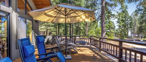 Une terrasse en bois avec des sièges d’extérieur et un grand parasol.