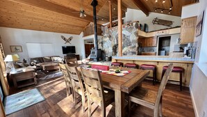 Amplia sala de estar con una mesa de comedor de madera, sillas, un sofá y una chimenea.