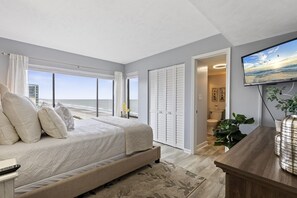 Enjoy ocean views from the comfort of this spacious bedroom featuring a large bed and a desk area.