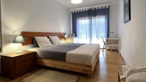 Quarto com cama de madeira, mesa de cabeceira, escrivaninha e cadeira.