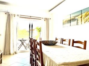 Uma área de refeições com uma mesa, cadeiras, uma tigela e um vaso de planta.