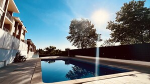 Uma área de piscina moderna com céu azul límpido, piscina e um edifício com varandas.
