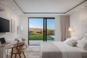 Et moderne hotelværelse med en stor seng, et skrivebord med en bærbar computer, en stol og et fjernsyn.