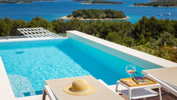 Uma piscina com vista clara para o mar e ilhas ao fundo.