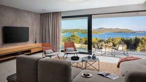 Un salon moderne doté d’un grand téléviseur, de sièges confortables et d’un balcon offrant une vue panoramique.
