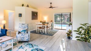 Un salon spacieux comprenant un coin repas, un ventilateur de plafond et donnant sur une piscine.