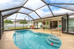 An indoor swimming pool with a glass ceiling, a pink flamingo float, and a clear view of the outside. - Coastal Getaway! Heated Pool, Private Patio, Fenced Yard, 5 miles to Beach! (Sebastian)