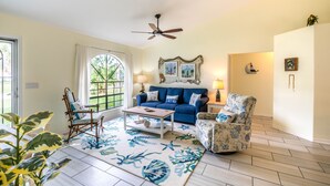 Un salon avec un canapé bleu, une table basse en bois et un tapis à motifs.