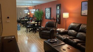 A modern living room with leather sofas, a dining area with a table and chairs, and a large plant. - Intimate Winter Oasis (Palm Springs)