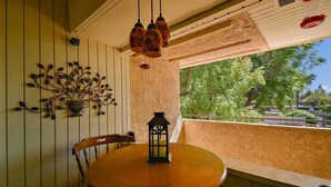 A round wooden table with a lantern on it, a chair, and a wall with a plant decoration. - Intimate Winter Oasis (Palm Springs)