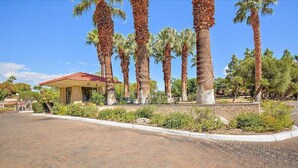 A building with a red roof and a paved area with palm trees. - Intimate Winter Oasis (Palm Springs)