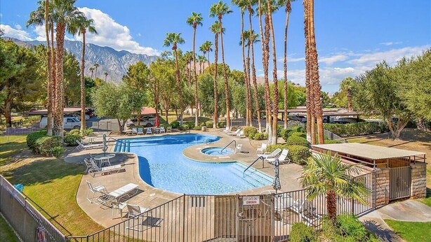 A swimming pool surrounded by palm trees and a mountain backdrop. - Intimate Winter Oasis (Palm Springs)