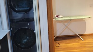 Una sala de lavandería con dos lavadoras apiladas y una plancha.