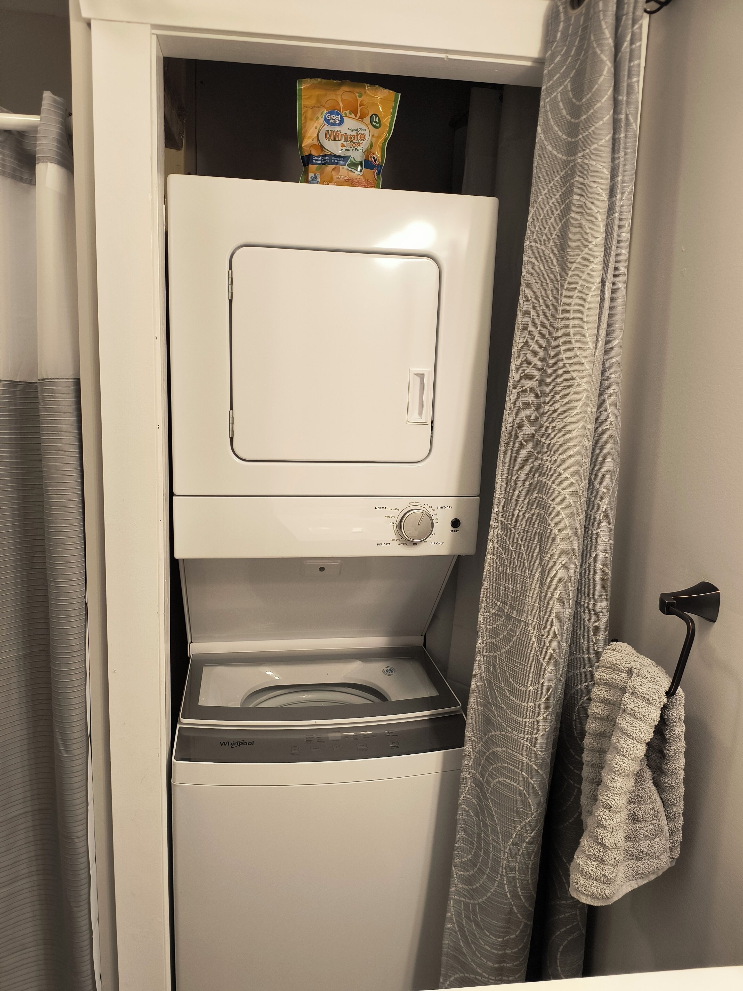 A compact washer and dryer unit with a control panel and a hanging laundry basket.