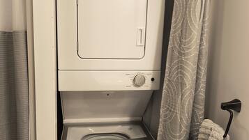 A compact washer and dryer unit with a control panel and a hanging laundry basket.
