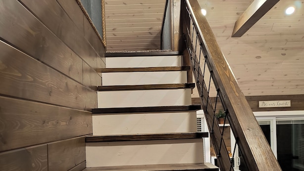 A wooden staircase with a metal railing leading to a landing.