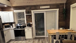 A modern kitchen with white cabinets, a built-in oven, and a dining area with a wooden table and chairs.
