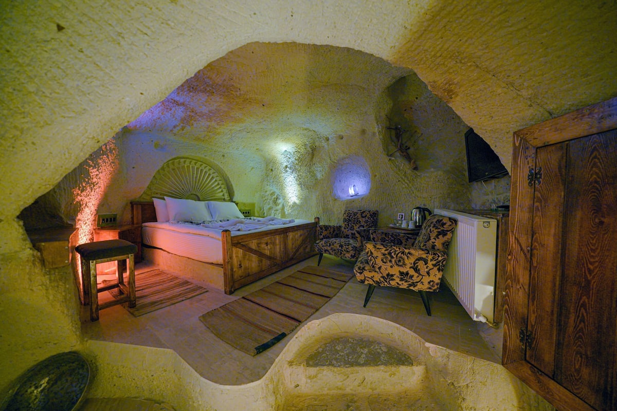 A cozy, rustic room with a bed, a wooden chair, a small table, and a bathtub.