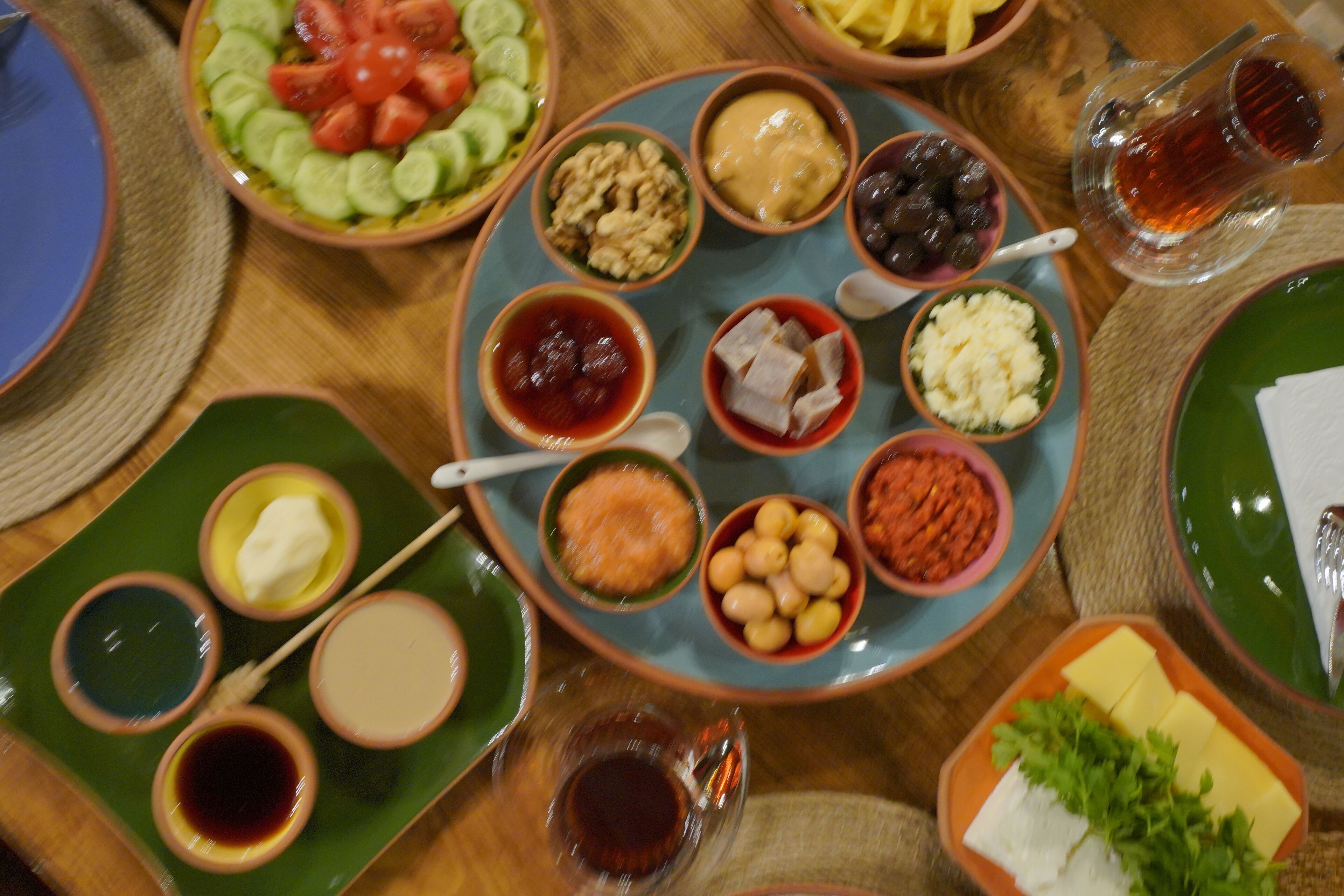 A table with various dishes and condiments, including bowls of nuts, olives, and cheese.