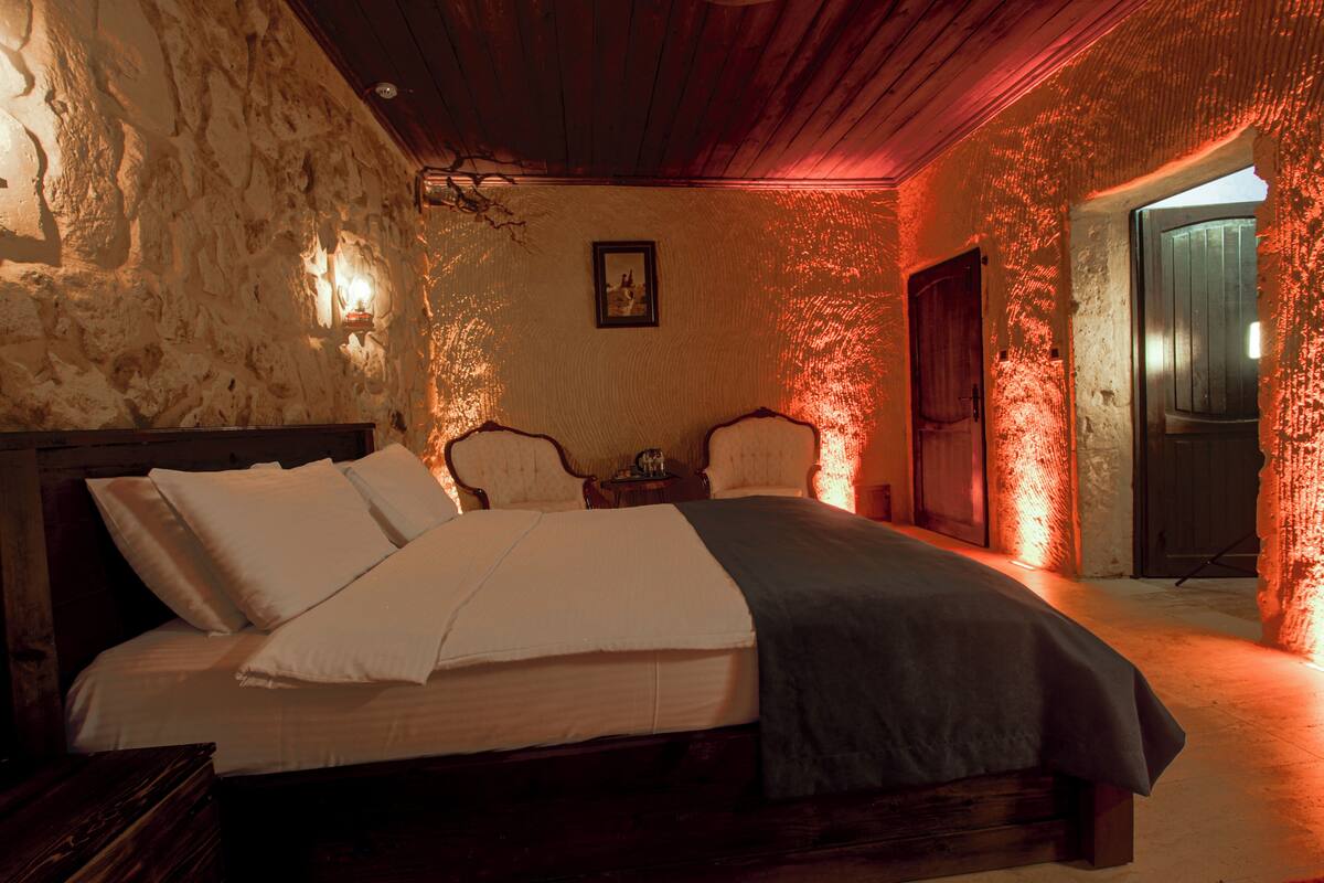A bedroom with a wooden bed, a nightstand, a chair, and a door.