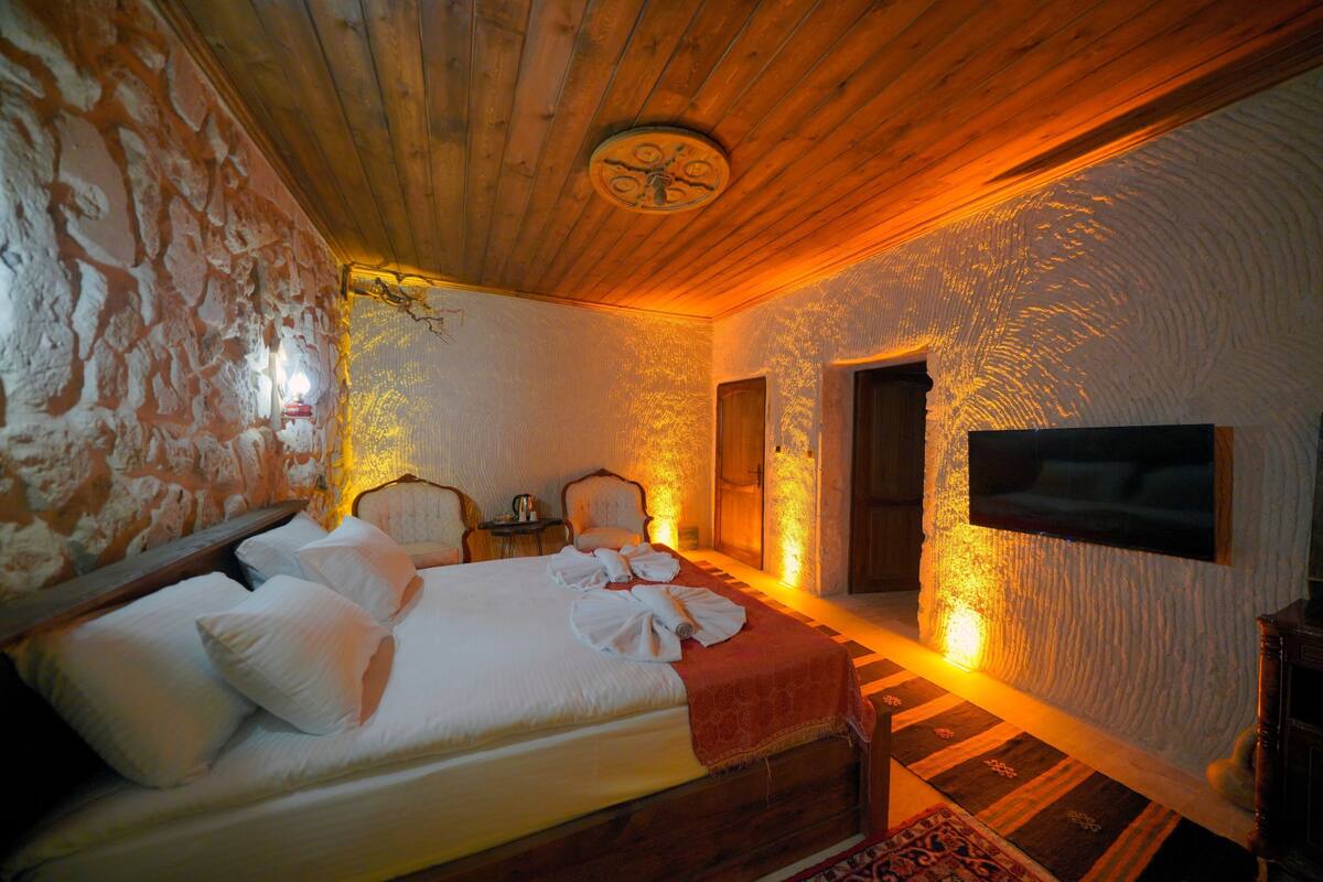 A room with a bed, a television, and a stone wall.