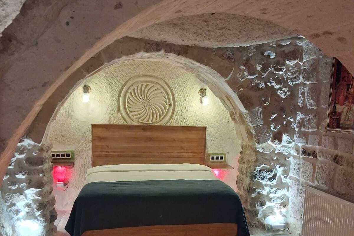 A bedroom with a wooden bed, stone walls, and a circular design on the ceiling.