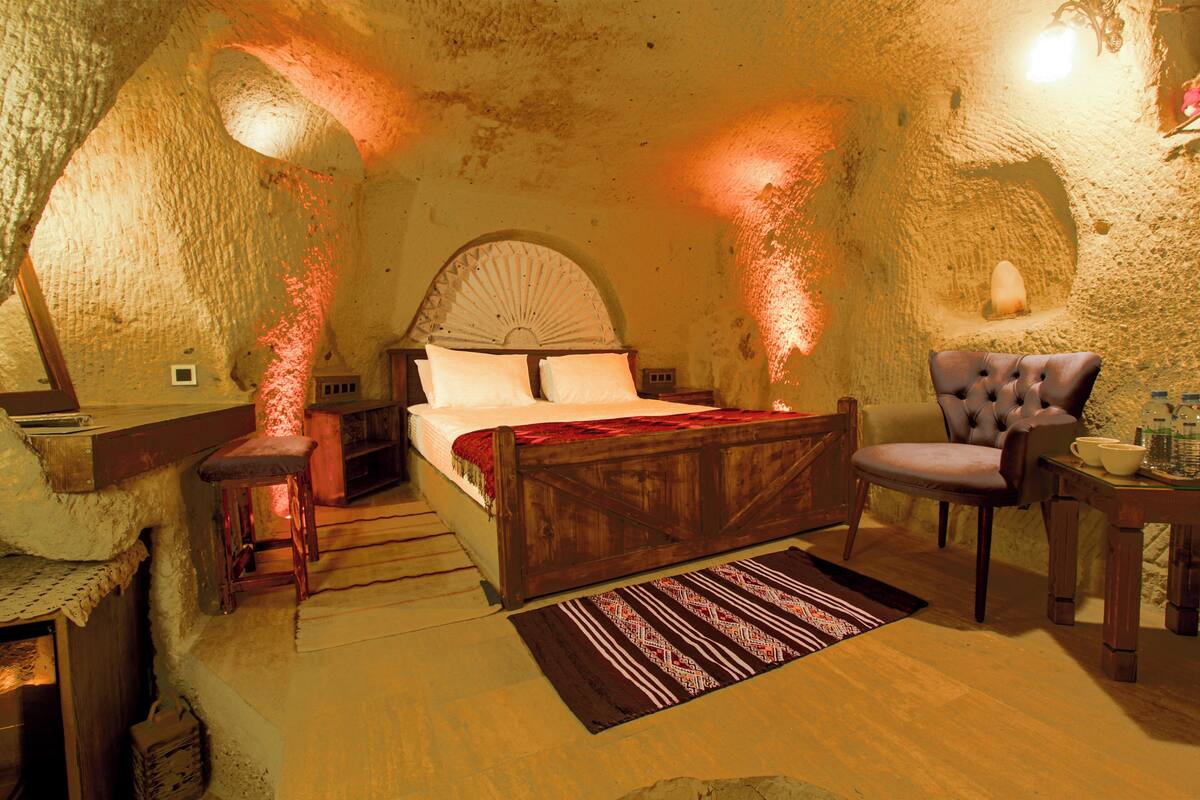 A bedroom with a wooden bed, a chair, a small table, and a rug.