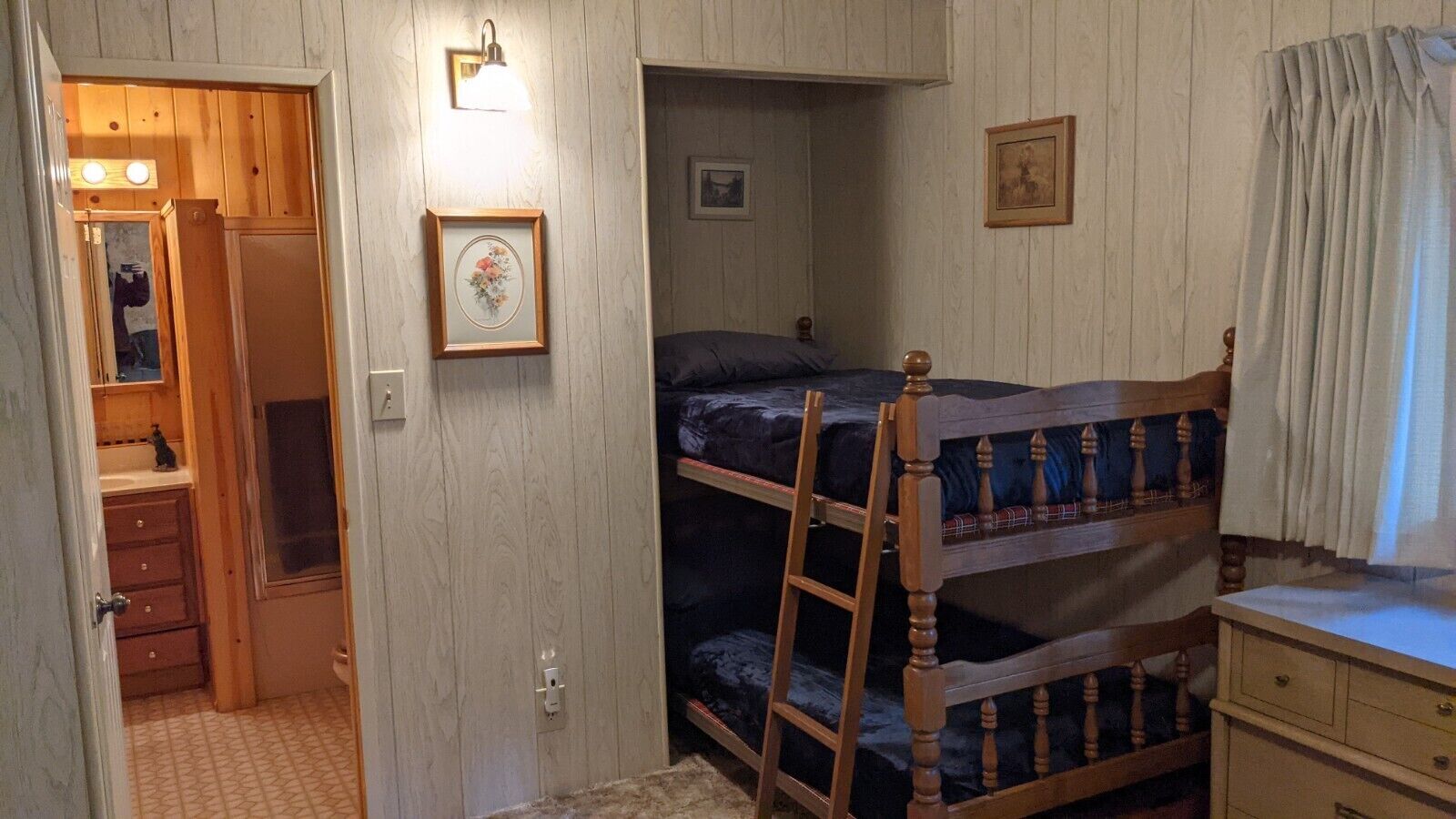 Una habitación con literas, un armario de madera y un escritorio pequeño.