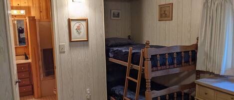 Una habitación con literas, un armario de madera y un escritorio pequeño.