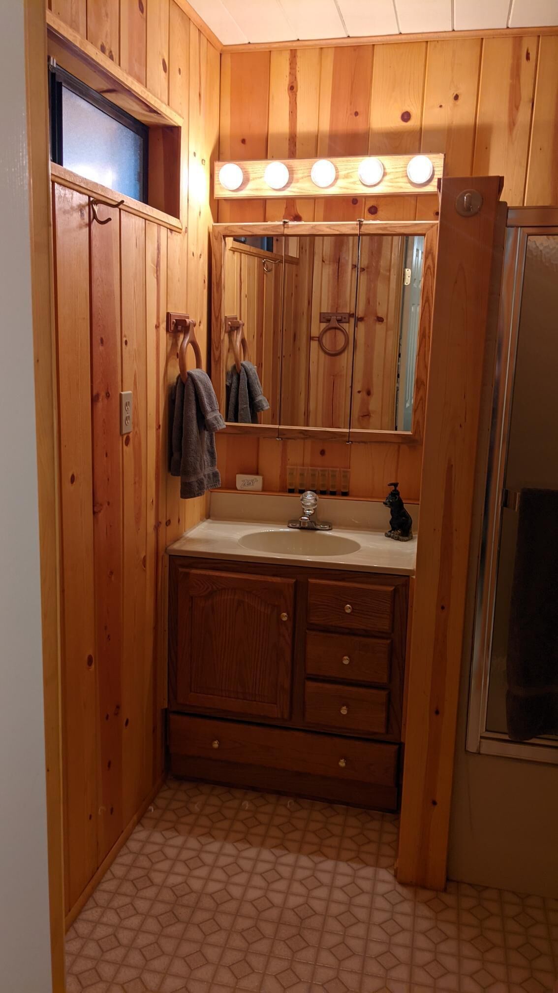 A wooden bathroom with a sink, mirror, and towel rack.