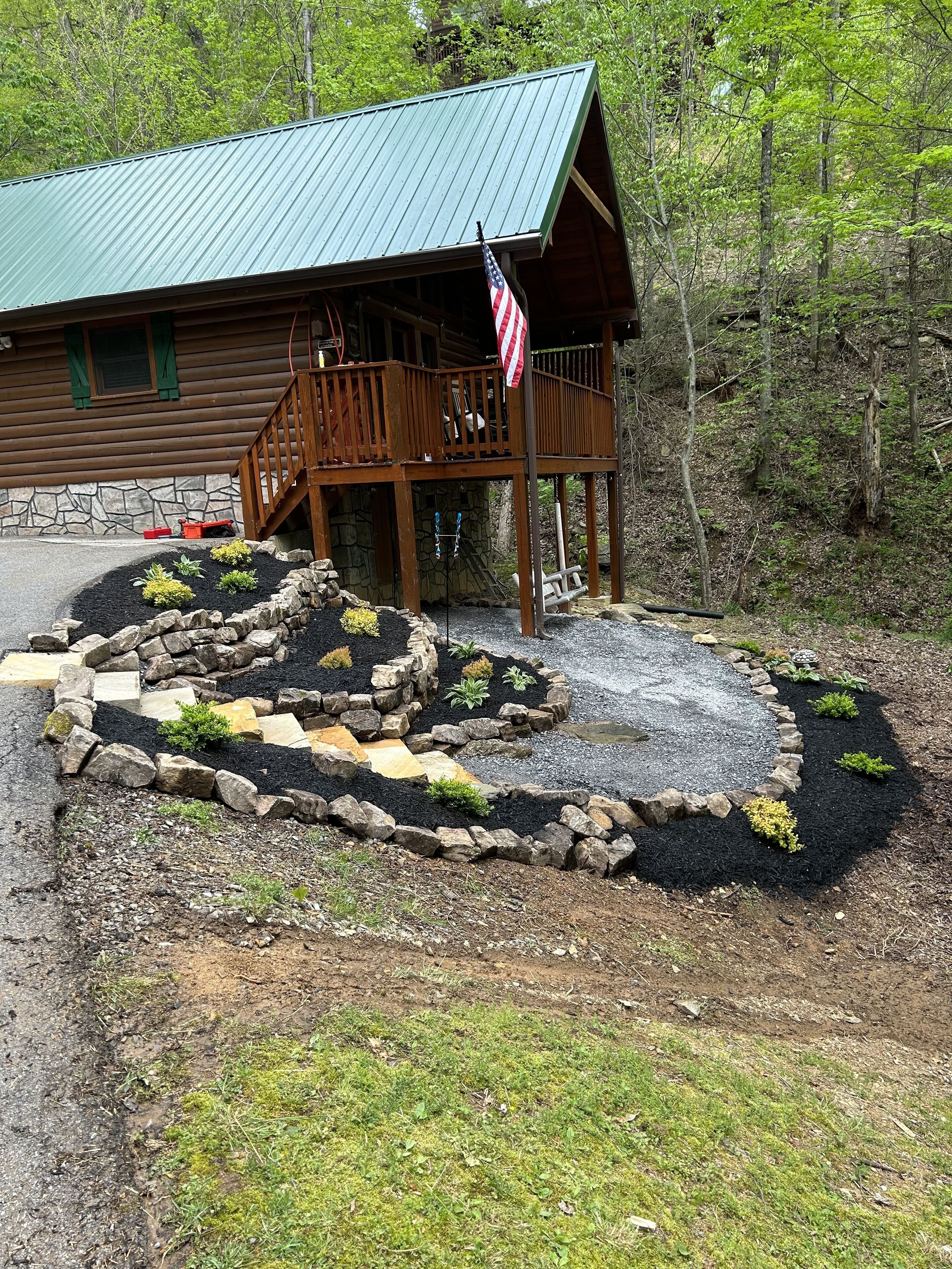 Uma cabana com base de pedra, deck de madeira e um mastro com a bandeira americana.