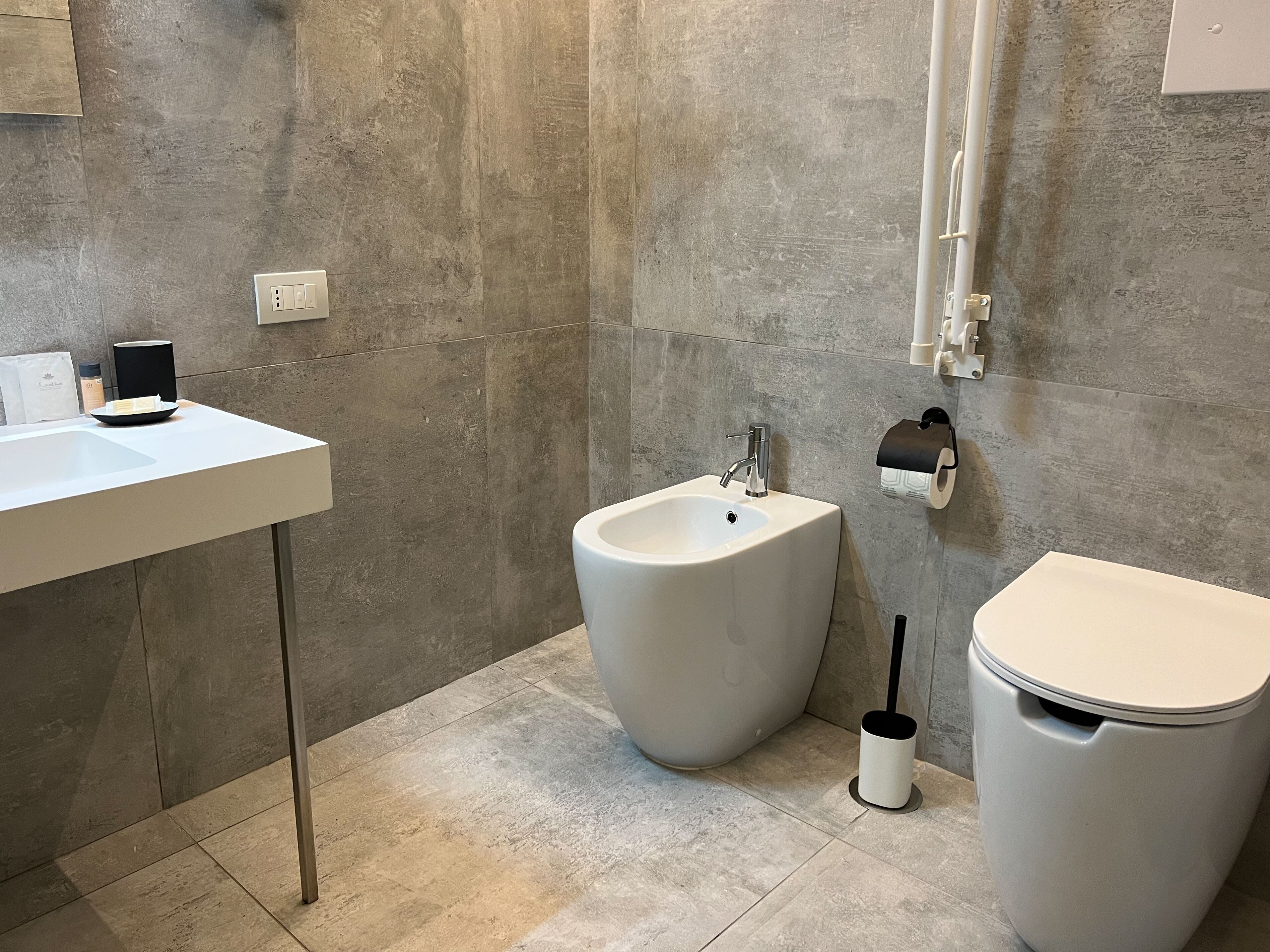 A modern bathroom with a white sink, bidet, and toilet.