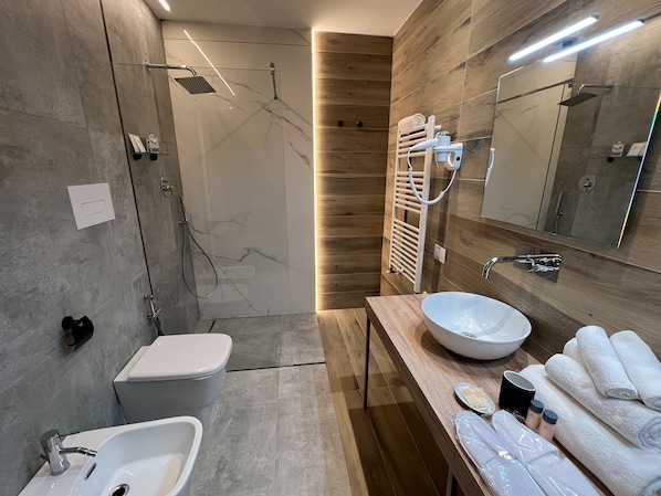 A modern bathroom with a glass-enclosed shower, a white sink, and a wooden vanity. - Korè Hotel (Nocera Superiore)