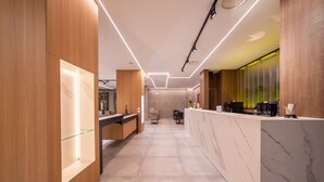 Un moderno vestíbulo de hotel con una recepción, zona de estar y un amplio escaparate de vidrio.