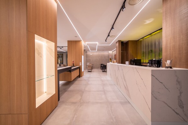 A modern hotel lobby with a reception desk, seating area, and a large glass display. - Korè Hotel (Nocera Superiore)