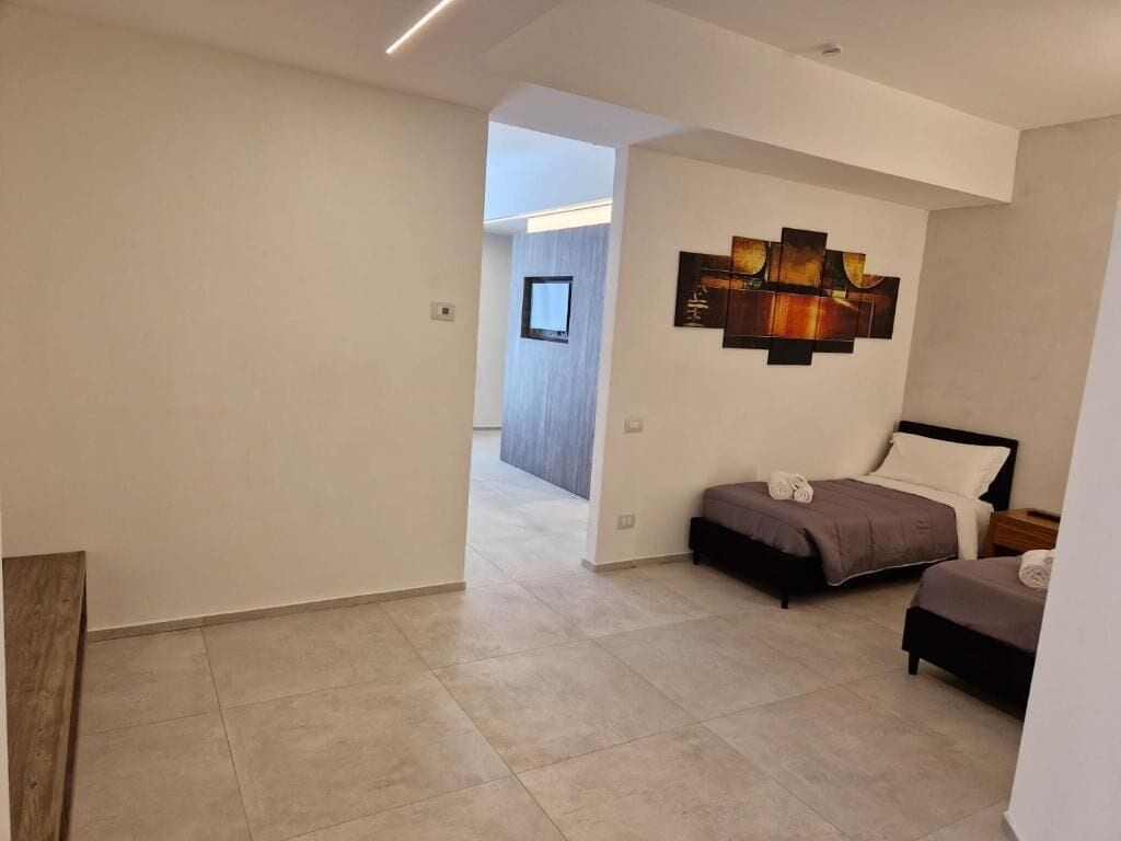 Une chambre moderne avec deux lits, une grande peinture abstraite et une vue sur une autre pièce.