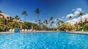 Ein Swimmingpool mit klarem, blauem Wasser, umgeben von Palmen und Liegestühlen.