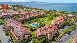 Ein Hochhaus-Hotel mit mehreren Balkonen, einem Schwimmbecken und Solaranlagen auf den Dächern.