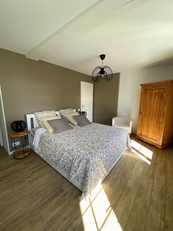 A bedroom with a bed, bedside table, chair, wardrobe, and a hanging light fixture. - Cocoon of the vines, Maison Tourangelle in the heart of Domaine Ansodelles (Benais)