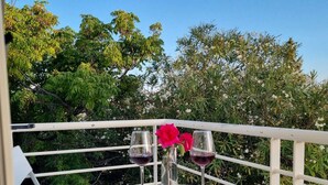 Ein Tisch im Freien mit weißer Uferbefestigung, zwei Weingläsern und einer rosa Blume, sowie einer Speisekarte.