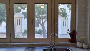 Eine Küche mit einem doppelten Spülbecken, beigen Schränken und einem Fenster mit Blick auf einen Baum und ein Haus.